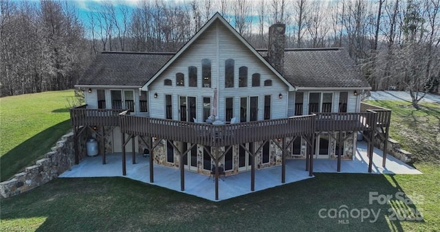 back of property with a deck, a lawn, and a patio area