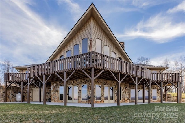 rear view of house with stone siding, a deck, and a yard