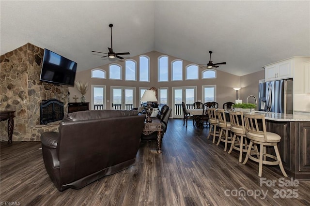 living area featuring a fireplace, dark wood finished floors, and a ceiling fan