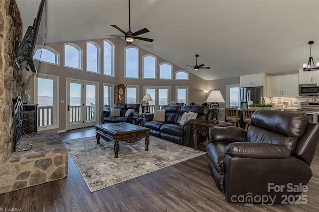 living area featuring dark wood-type flooring, french doors, high vaulted ceiling, and ceiling fan with notable chandelier