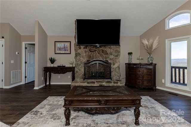 sitting room with vaulted ceiling, a stone fireplace, wood finished floors, and visible vents