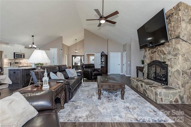 living room with ceiling fan with notable chandelier, high vaulted ceiling, a fireplace, and wood finished floors