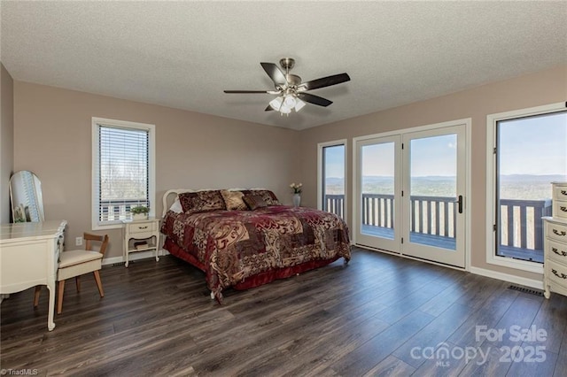 bedroom with a textured ceiling, access to outside, dark wood-type flooring, and multiple windows