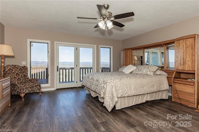 bedroom with dark wood finished floors, ceiling fan, access to outside, a textured ceiling, and a mountain view