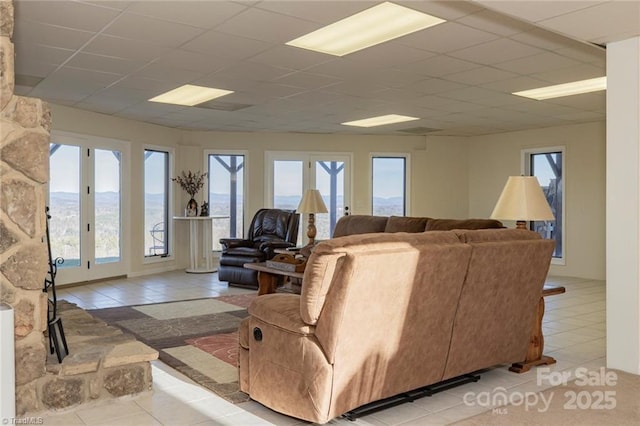 tiled living area with french doors and a drop ceiling