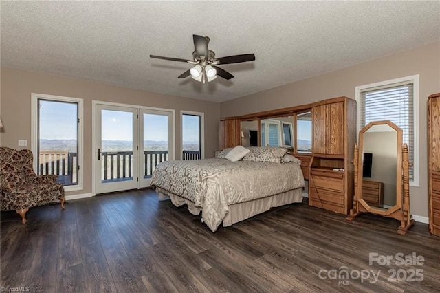 bedroom with access to exterior, multiple windows, dark wood-style floors, and a textured ceiling