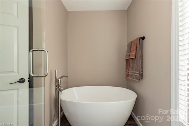 bathroom featuring a freestanding tub and baseboards