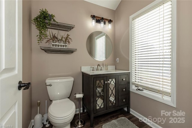 bathroom with baseboards, vanity, toilet, and wood finished floors