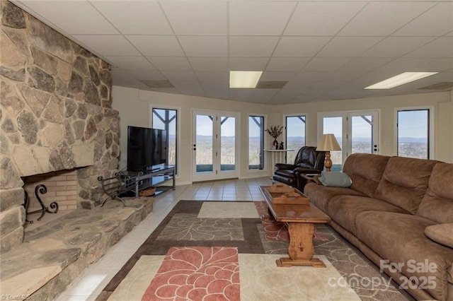 tiled living area with a wealth of natural light, a drop ceiling, and french doors