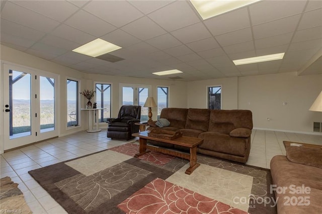 tiled living area featuring a drop ceiling, visible vents, and baseboards