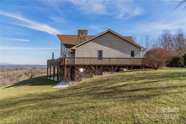 view of side of property featuring a chimney, a deck, a patio, and a yard