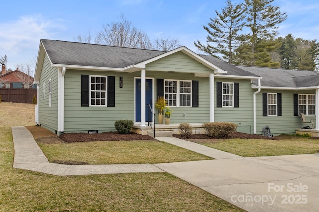 view of front of home with a shingled roof, crawl space, covered porch, fence, and a front yard