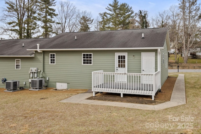 back of property with central AC, a yard, and roof with shingles