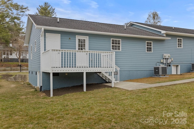 rear view of property featuring roof with shingles, central AC unit, and a yard