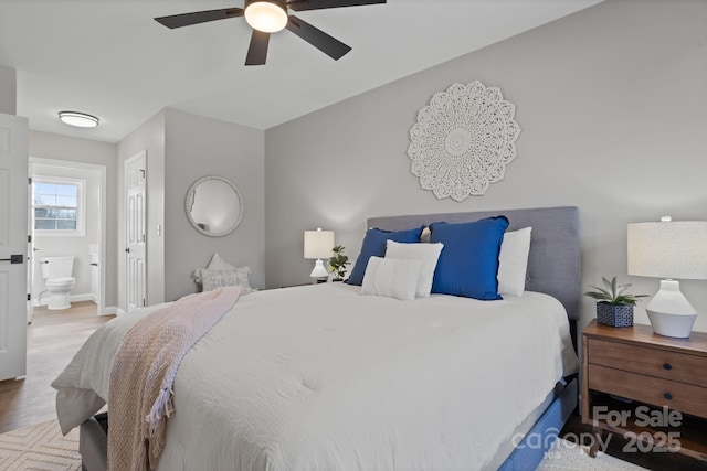 bedroom with baseboards, ceiling fan, ensuite bathroom, and wood finished floors