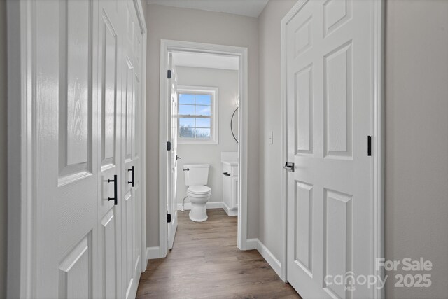 hall featuring dark wood-style flooring and baseboards