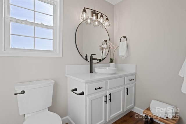 bathroom with toilet, baseboards, wood finished floors, and vanity