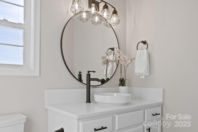 half bath featuring vanity, toilet, and an inviting chandelier