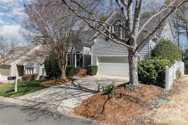 view of front facade with driveway, an attached garage, and fence