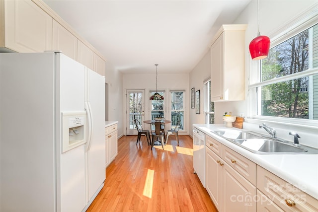 kitchen with light countertops, white appliances, a sink, and pendant lighting