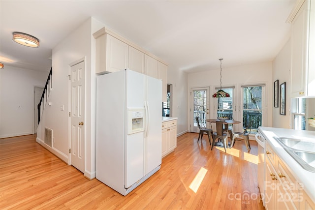 kitchen with visible vents, white appliances, light countertops, and light wood-style flooring