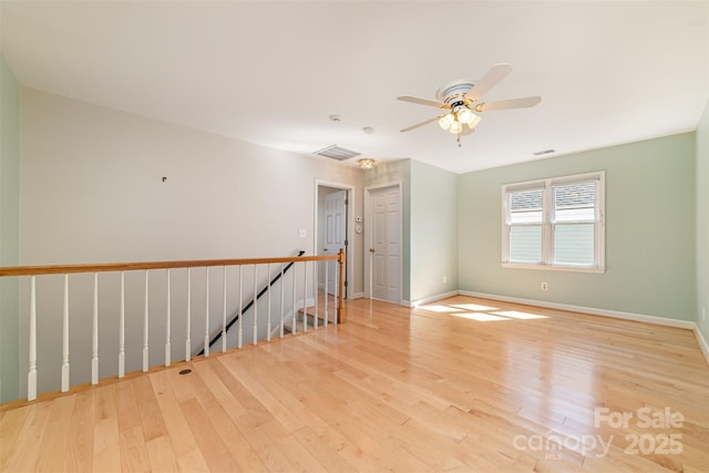 empty room featuring visible vents, ceiling fan, baseboards, and wood finished floors