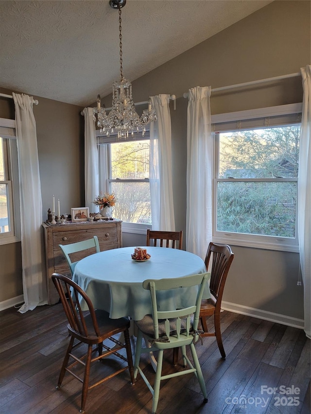 dining area featuring dark wood-style flooring, vaulted ceiling, a textured ceiling, and baseboards