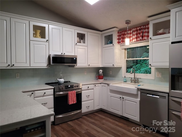 kitchen featuring white cabinets, dark wood finished floors, decorative light fixtures, stainless steel appliances, and a sink