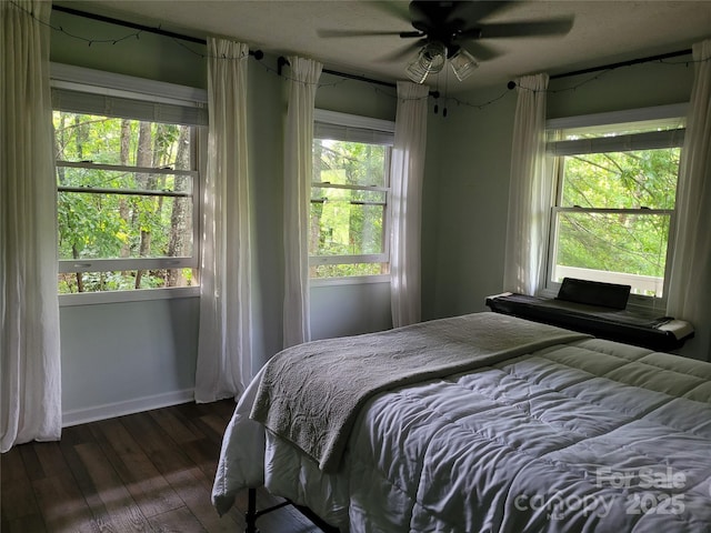 bedroom featuring dark wood-style floors, a ceiling fan, and baseboards