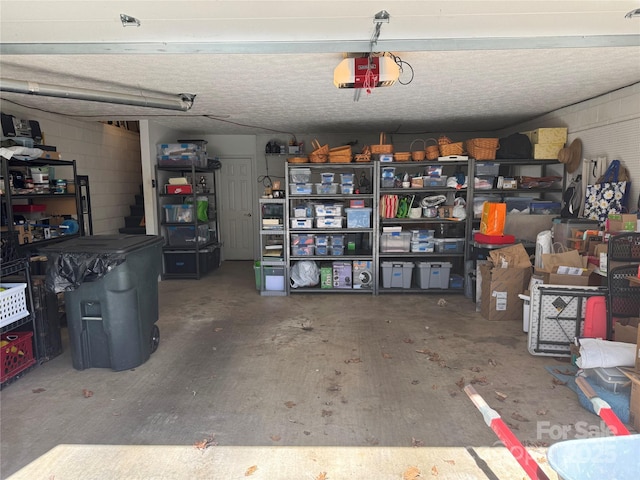 garage featuring concrete block wall and a garage door opener