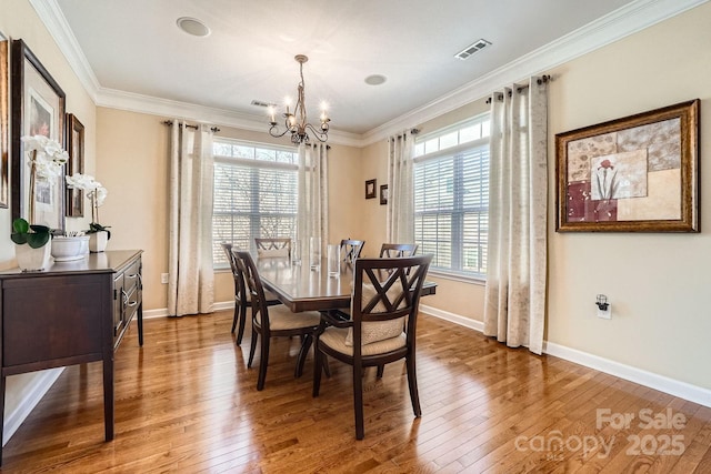 dining room featuring ornamental molding, a healthy amount of sunlight, a notable chandelier, and hardwood / wood-style floors