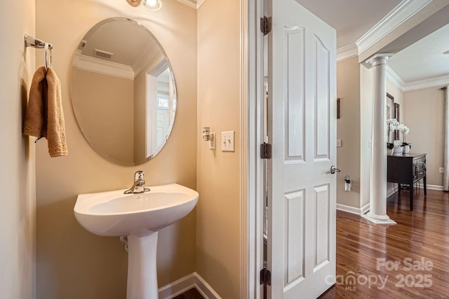 bathroom featuring baseboards, crown molding, ornate columns, and wood finished floors