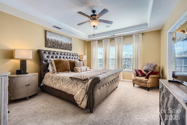 bedroom with light carpet, a tray ceiling, visible vents, and crown molding