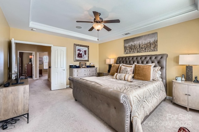 bedroom with visible vents, baseboards, light colored carpet, a tray ceiling, and crown molding