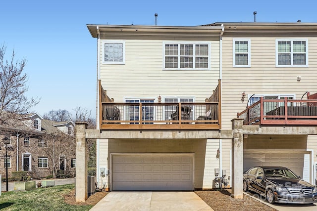 back of property with an attached garage, a balcony, central AC, and concrete driveway