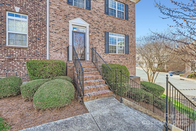 view of exterior entry featuring fence and brick siding