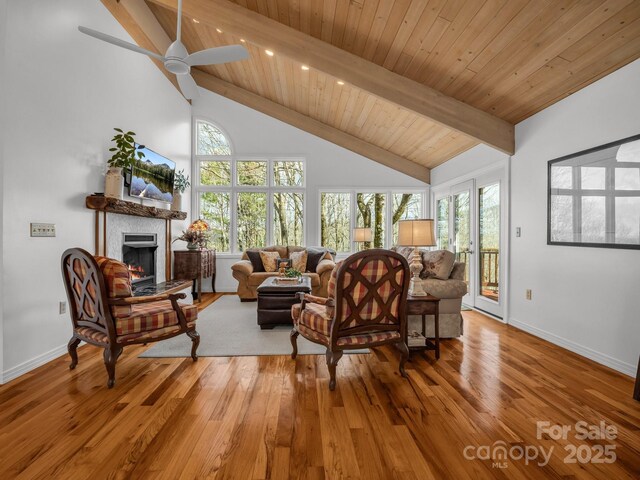 209 Walnut Ridge Rd, Brevard, NC 28712 - living area with wood finished floors, beam ceiling, a warm lit fireplace, and plenty of natural light