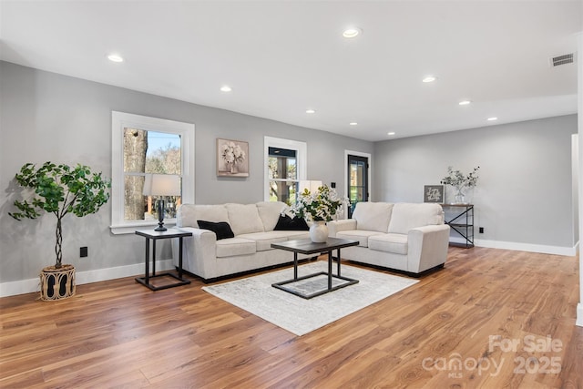 living room featuring light wood-style flooring, recessed lighting, and visible vents