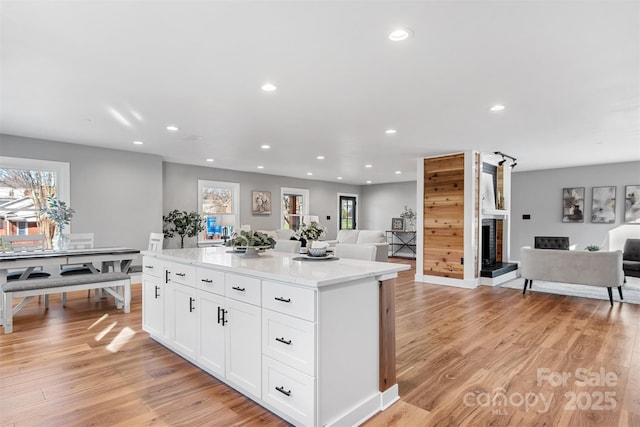 kitchen with recessed lighting, white cabinets, light wood-style floors, open floor plan, and a center island