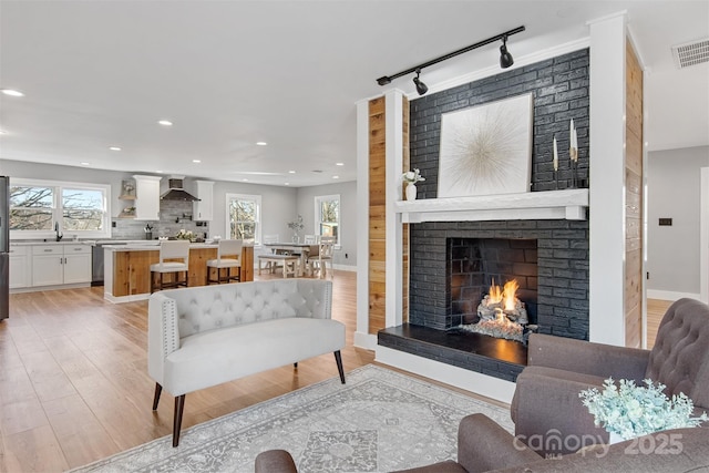 living room with visible vents, baseboards, recessed lighting, light wood-style flooring, and a fireplace