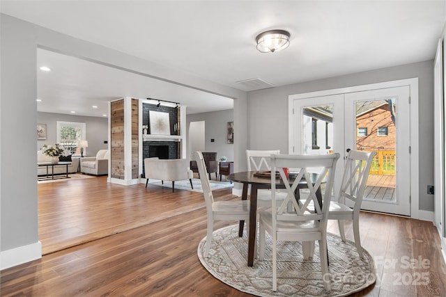 dining space with baseboards, recessed lighting, a fireplace, french doors, and wood-type flooring