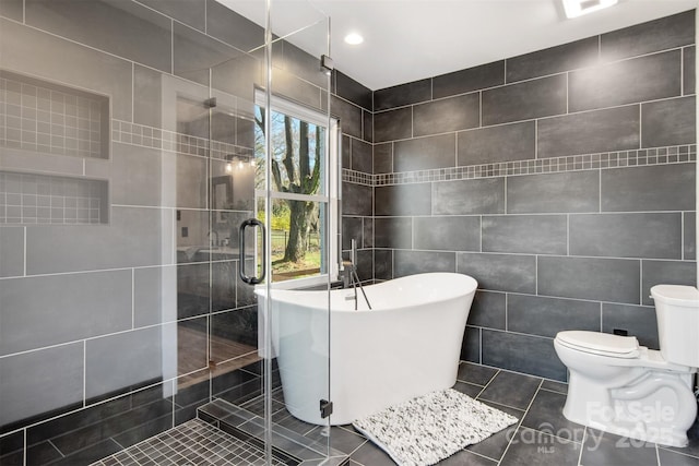 full bathroom with tile patterned floors, toilet, tile walls, a shower stall, and a freestanding bath