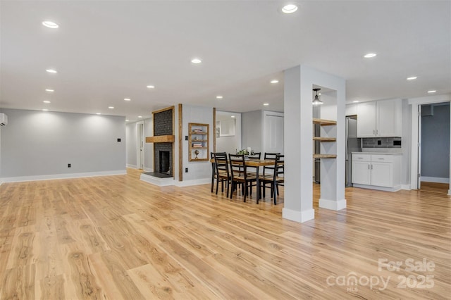 living room featuring a brick fireplace, recessed lighting, baseboards, and light wood finished floors