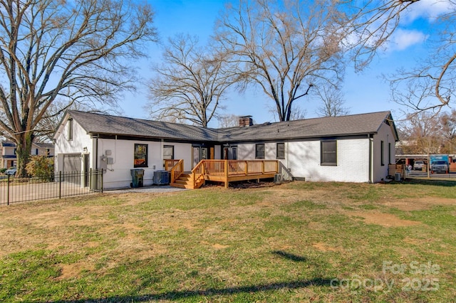 rear view of property featuring a lawn, fence, a wooden deck, brick siding, and a chimney