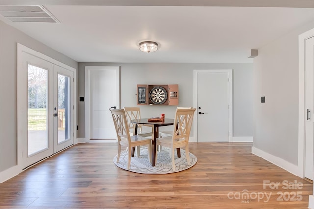 dining room featuring visible vents, baseboards, french doors, and light wood finished floors