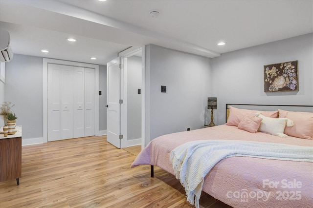 bedroom with a closet, recessed lighting, baseboards, and light wood-style floors