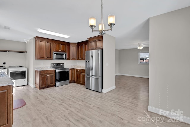 kitchen with washing machine and dryer, appliances with stainless steel finishes, light countertops, and light wood-style floors