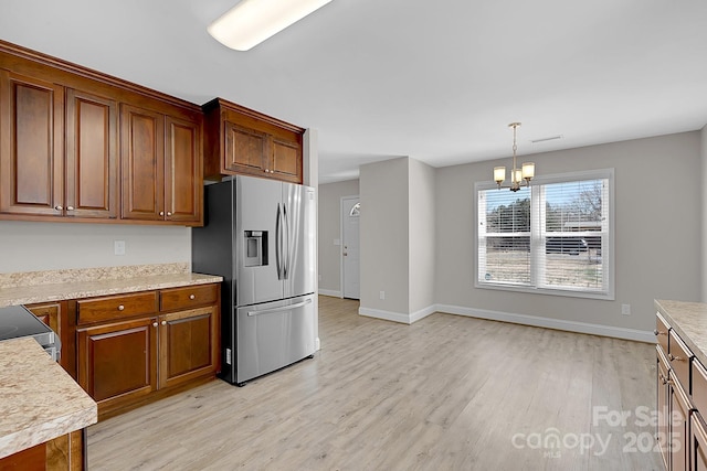 kitchen featuring light countertops, light wood-style floors, stainless steel refrigerator with ice dispenser, and a chandelier