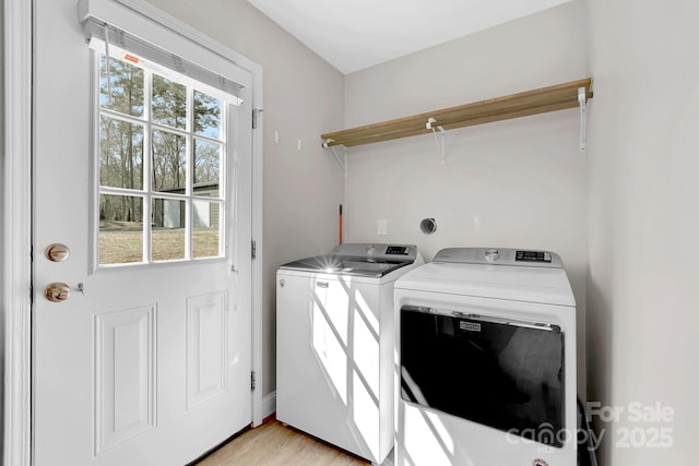 clothes washing area with light wood-style floors, separate washer and dryer, and laundry area