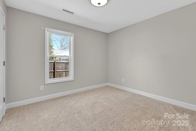 carpeted spare room featuring visible vents and baseboards